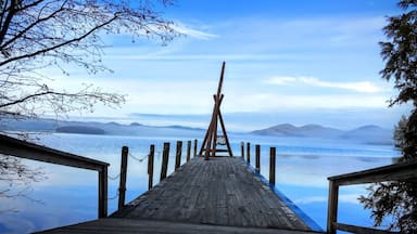 A wooden pier leading to a calm lake with mountains in the background.