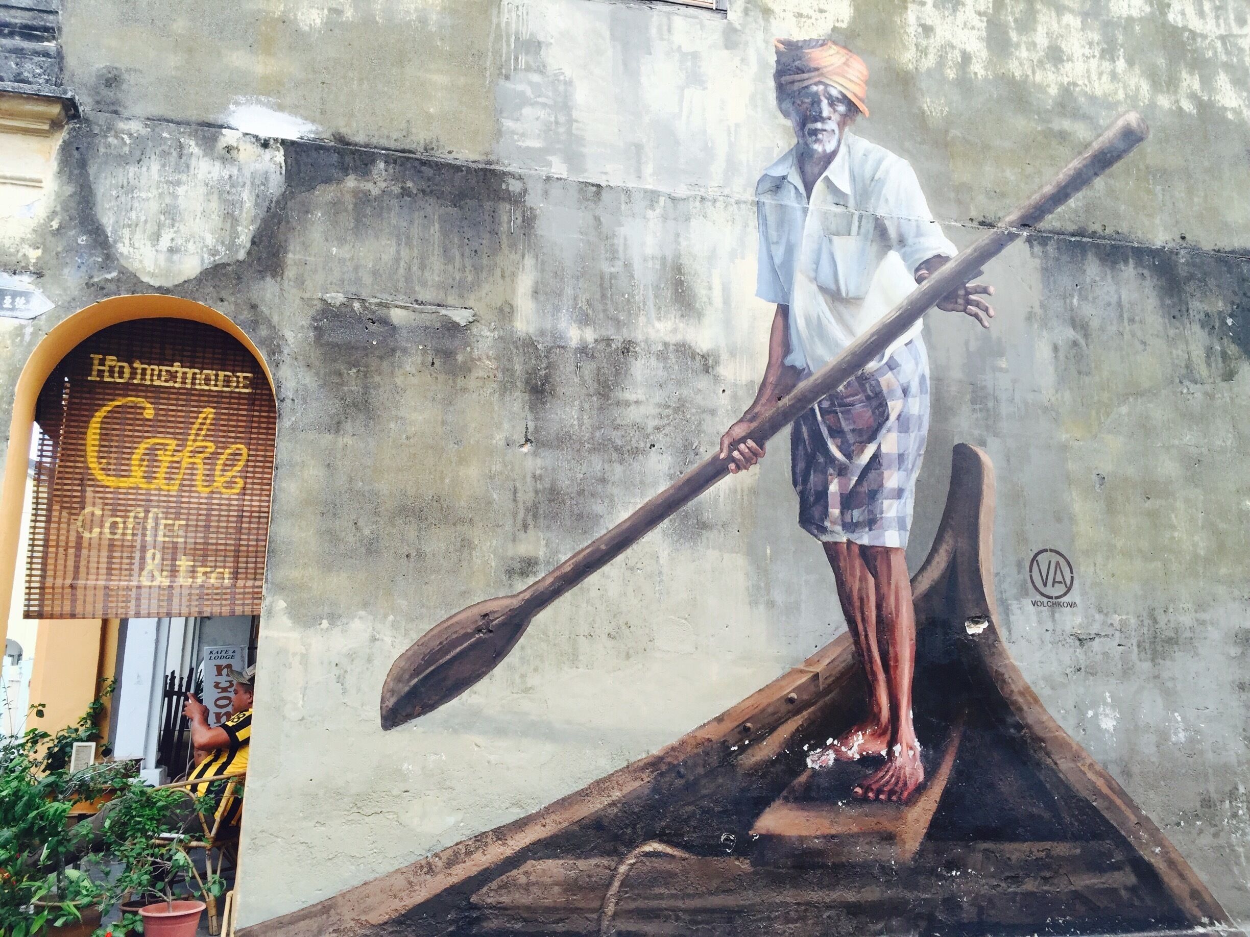 Um mural retrata um homem em um barco numa parede de concreto.