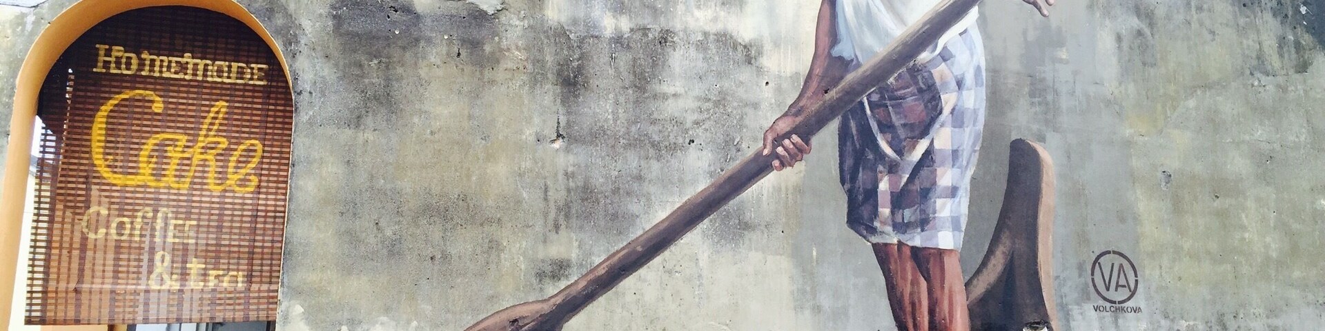 Um mural retrata um homem em um barco numa parede de concreto.