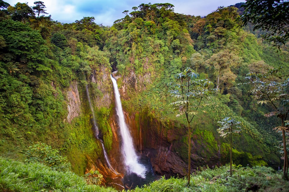 A waterfall cascading down a lush, green mountain.