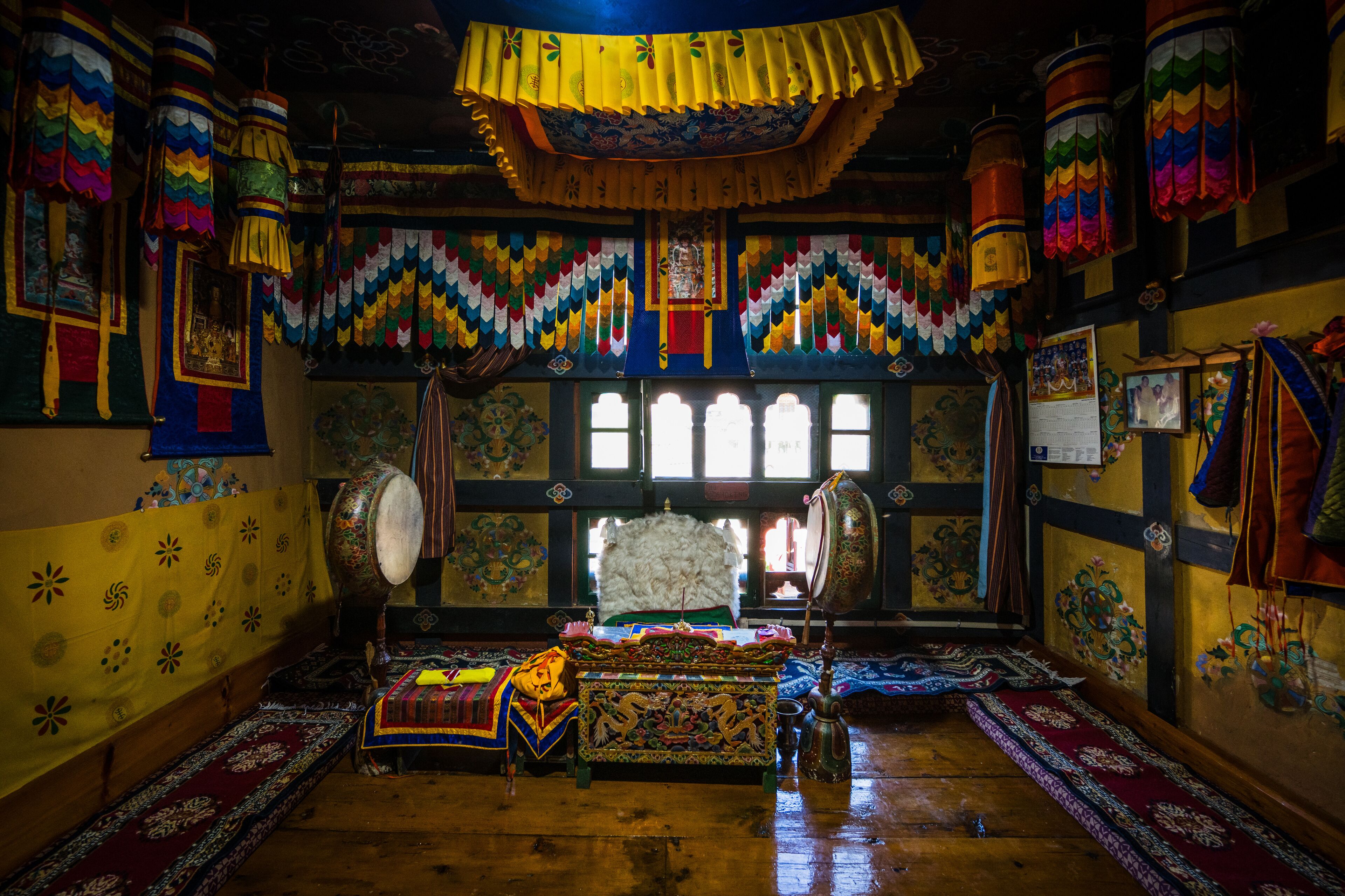 A traditional room with colorful decorations, a large drum, and a throne-like chair.