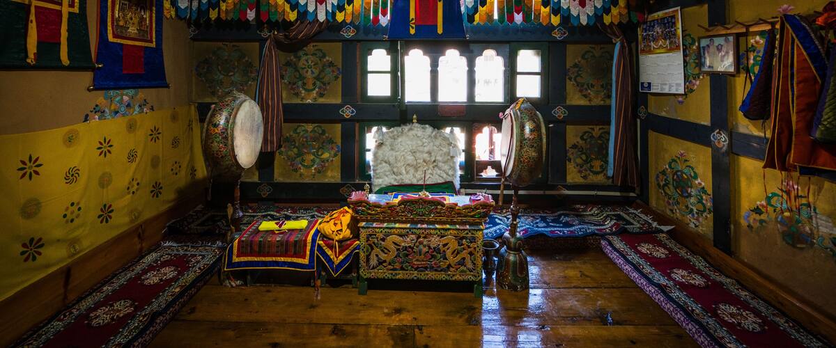 A traditional room with colorful decorations, a large drum, and a throne-like chair.