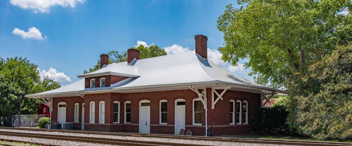 A red brick train station with white trim and a peaked roof.