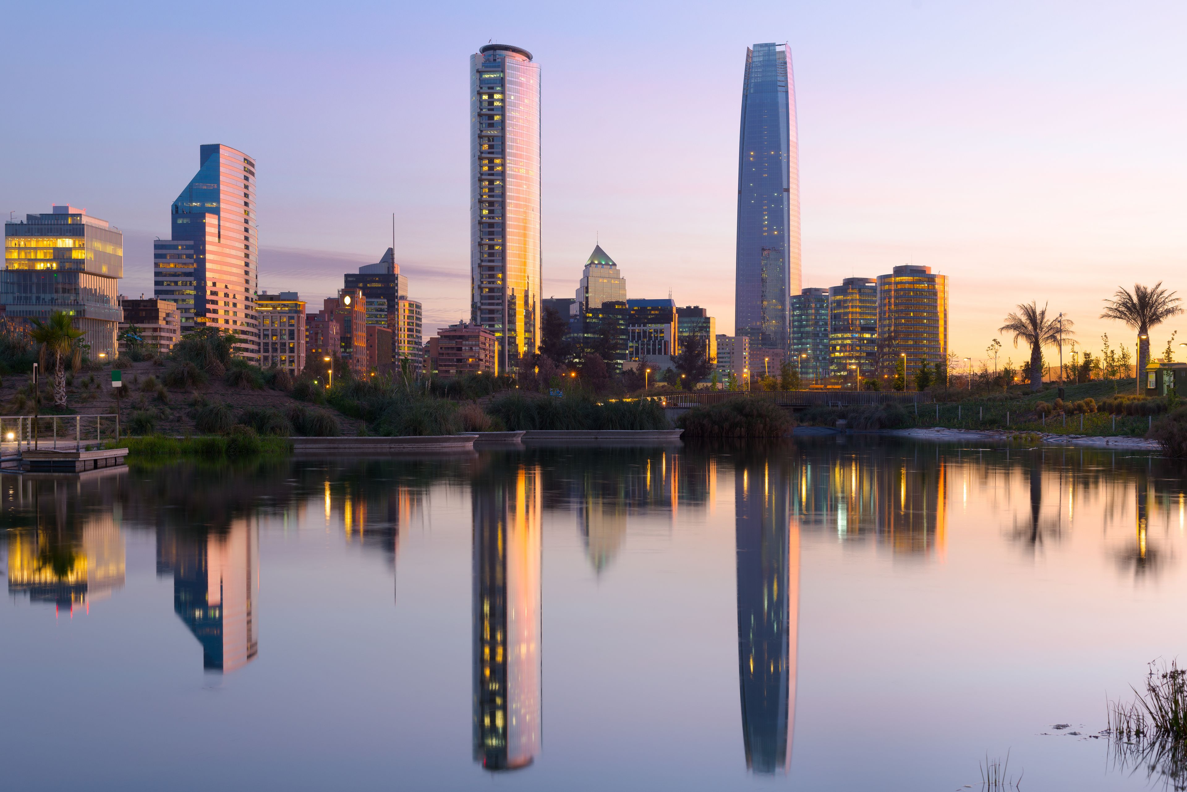 A city skyline with modern skyscrapers and a calm body of water reflecting the buildings.