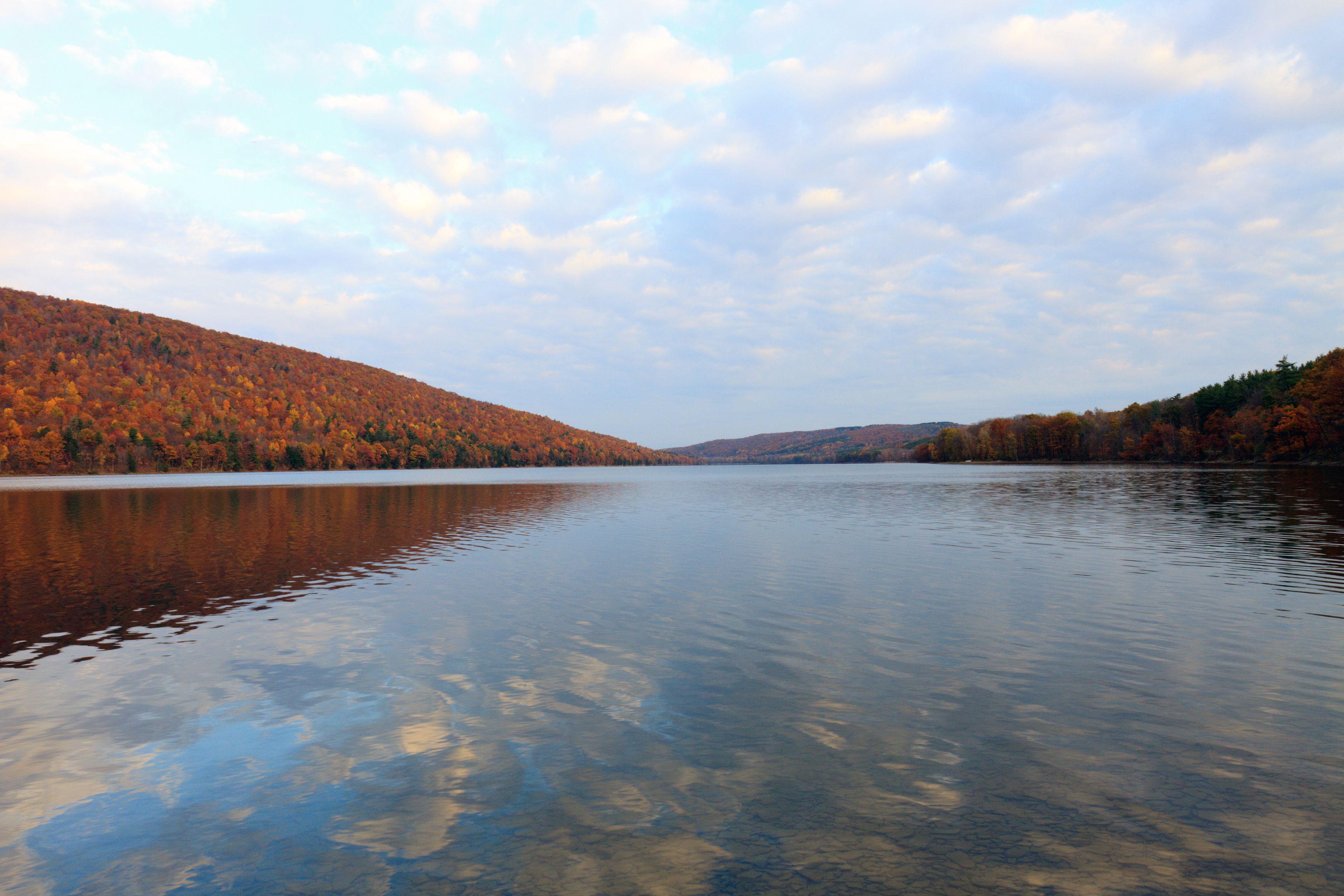 A calm lake with autumn foliage on the surrounding hills.