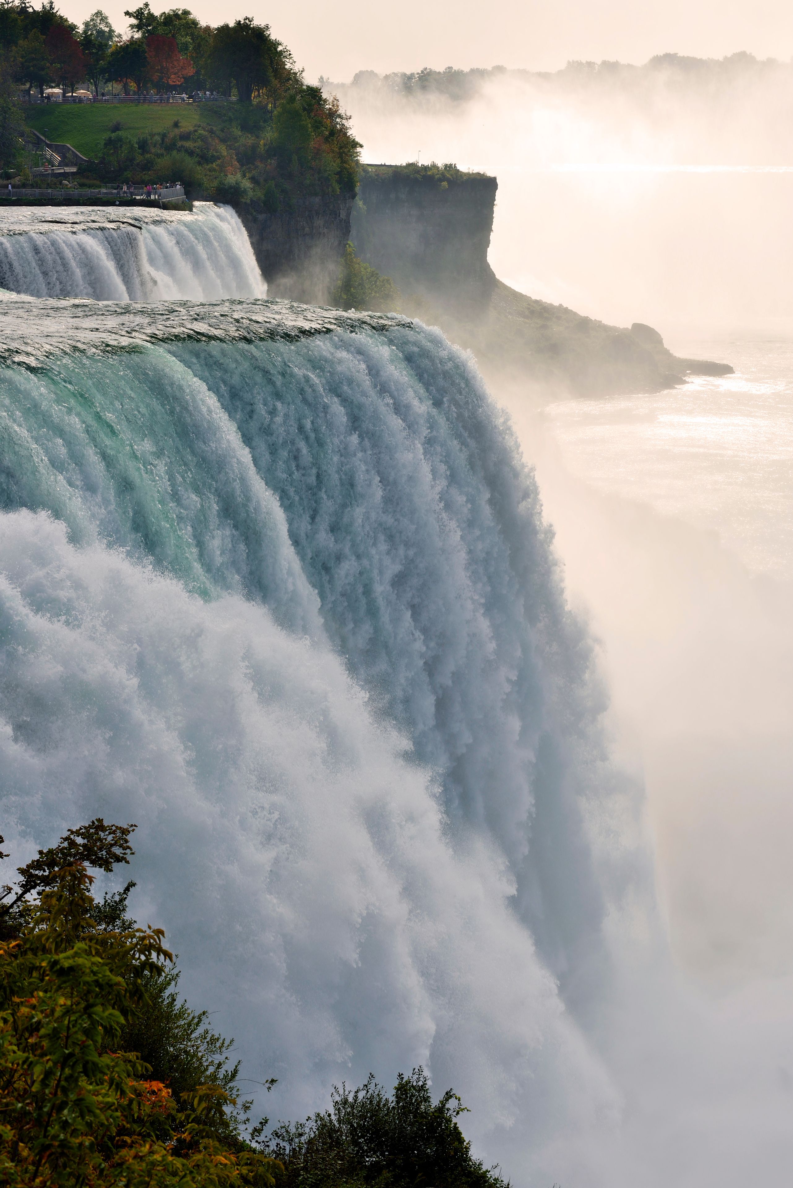 A large waterfall cascading down a cliff, surrounded by lush greenery and mist.