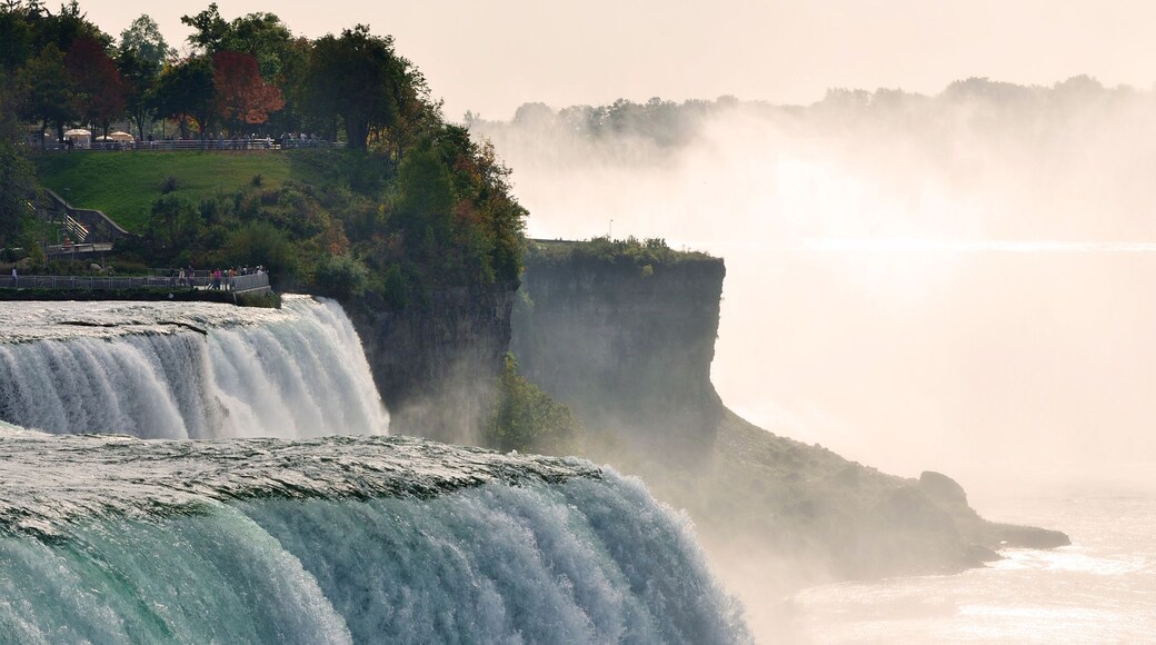 A large waterfall cascading down a cliff, surrounded by lush greenery and mist.