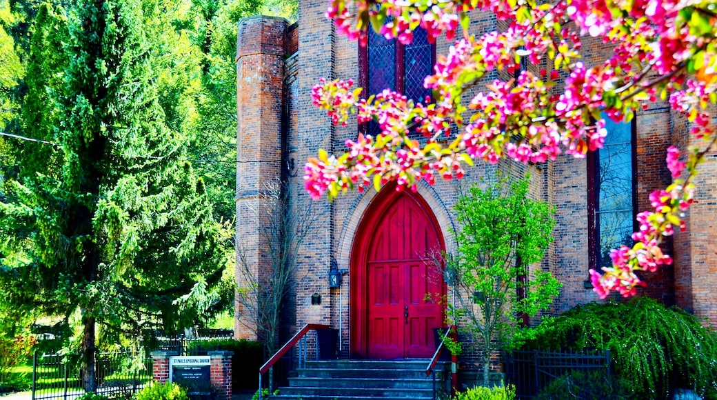 Une église en briques avec une porte rouge et un escalier menant à l’entrée.