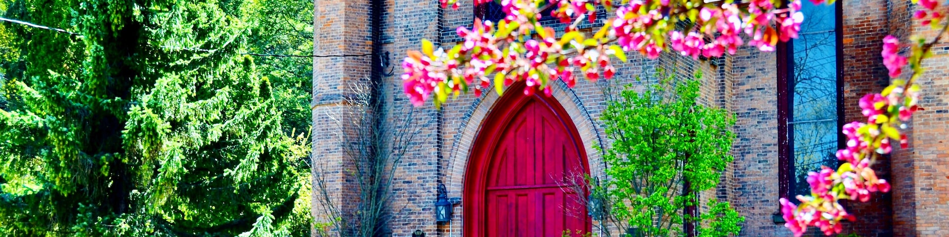 A brick church with a red door and a staircase leading up to it.
