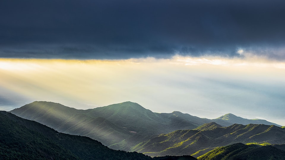 A view of the Tyndall effect and wind turbines at sunrise on Queya Mountain in Heyuan, Guangdong.