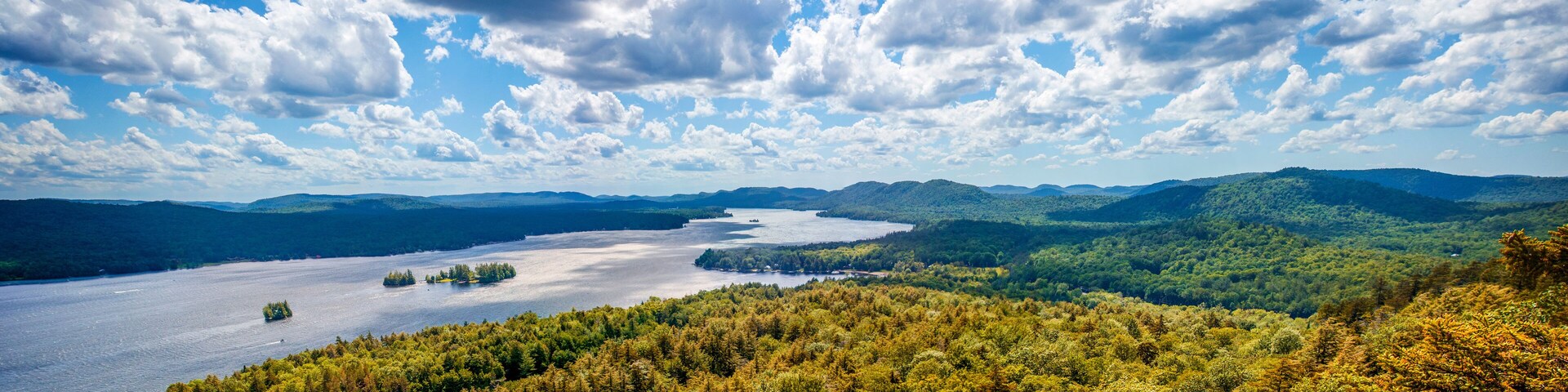 Fulton Chain Lakes view from the Adirondack Mountains in Upstate New York. Taken from the mountain summit after a short hiking trail. Lots of trees and clouds over the water. Camping in the Catskills