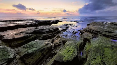 Uma linha costeira rochosa com o pôr do sol ao fundo.