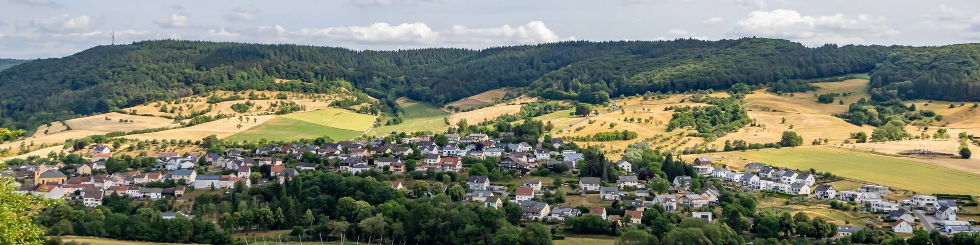 A rural landscape with rolling hills, a small village, and a river.