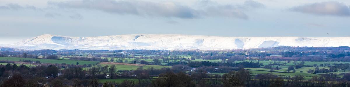 A snow-covered mountain with a valley in the foreground.