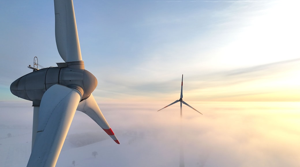 Deux éoliennes dans un paysage brumeux.