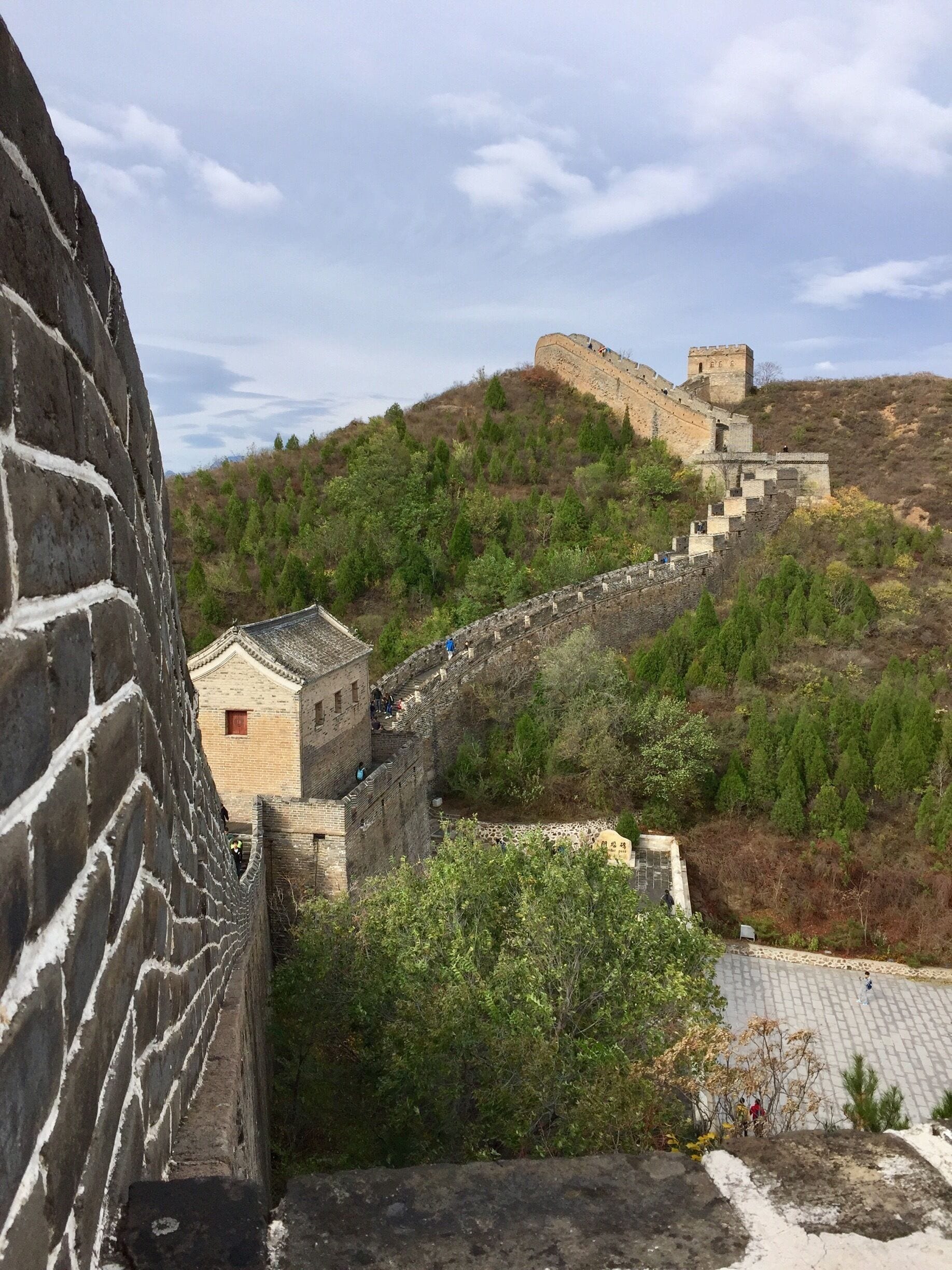 The Great Wall of China with a section of the wall running alongside a forested hill.