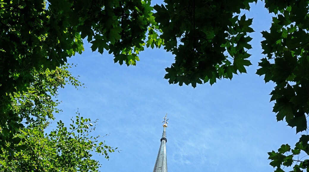 A church tower with a clock and a spire against a clear blue sky.