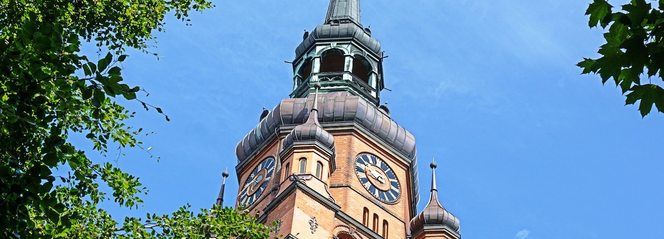 A church tower with a clock and a spire against a clear blue sky.
