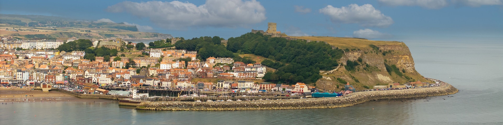 Aerial photo of Scarborough seafront and castle. Scarborough is a seaside town and civil parish in the district and county of North Yorkshire, England. With a population of 61,749