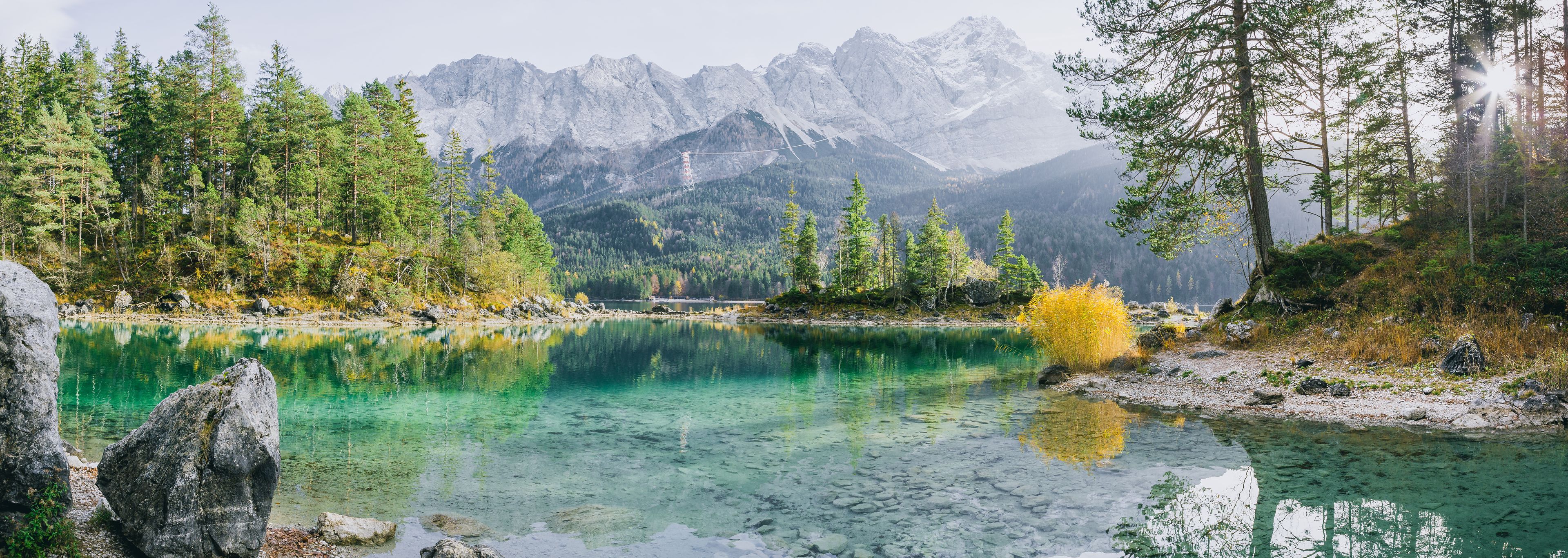 Un lac de montagne aux eaux cristallines, entouré d’une forêt dense et de montagnes escarpées.