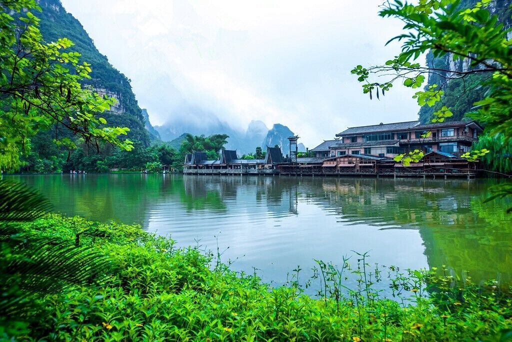A serene lake surrounded by lush greenery and traditional architecture.