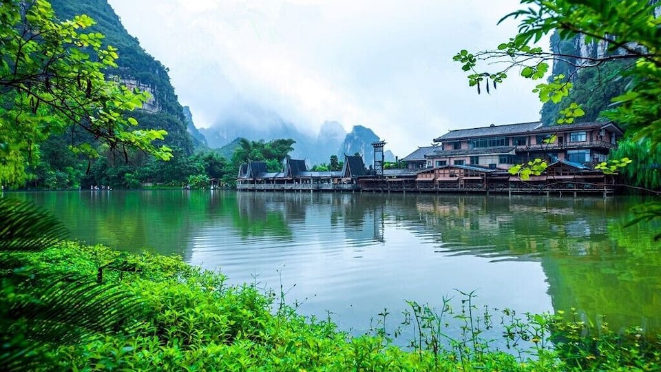 A serene lake surrounded by lush greenery and traditional architecture.
