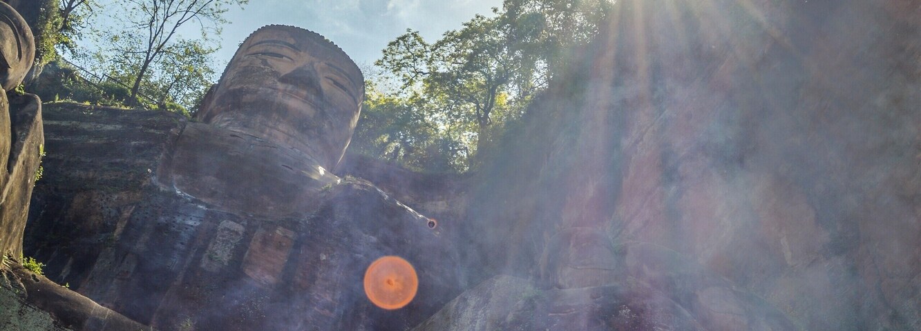Uma grande estátua de Buda de pedra, rodeada por árvores e névoa.