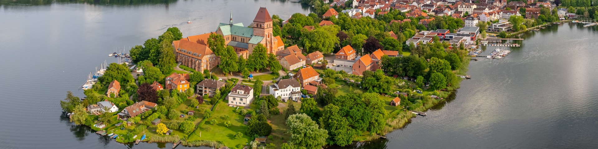 Eine Stadt am Seeufer mit einer markanten Kirche, Wohnhäusern und einem Yachthafen.