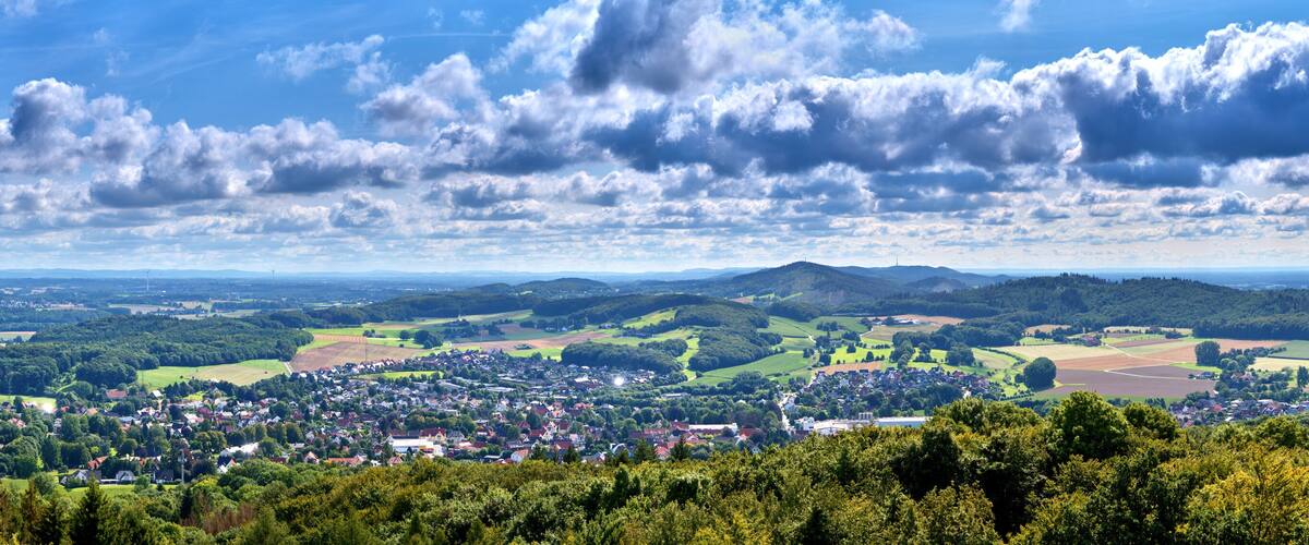 Panorama of villages on the edge of Teutoburg Forest near Osnabruck in Germany above the tree tops and with cloudy sky