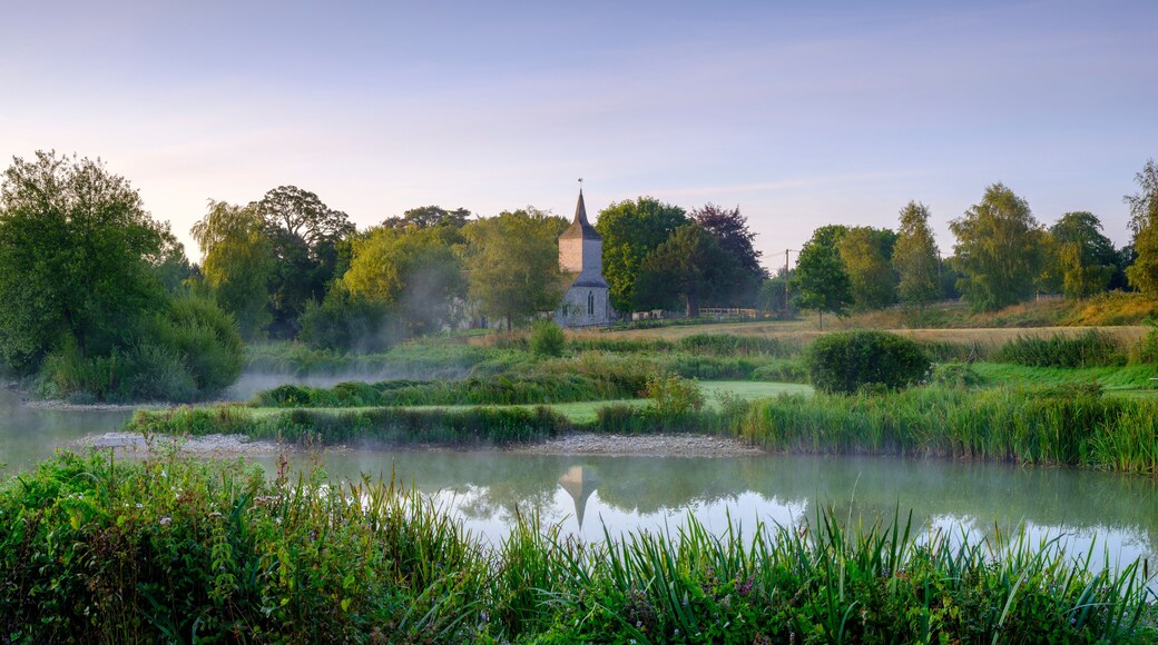 Misty dawn light on Stoke Charity village pond and St Michael's Church, Hampshire, UK