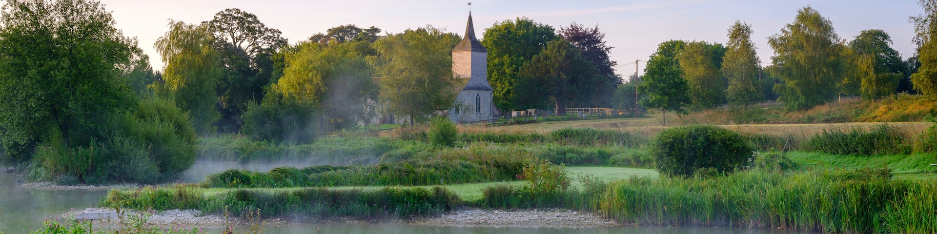 Misty dawn light on Stoke Charity village pond and St Michael's Church, Hampshire, UK