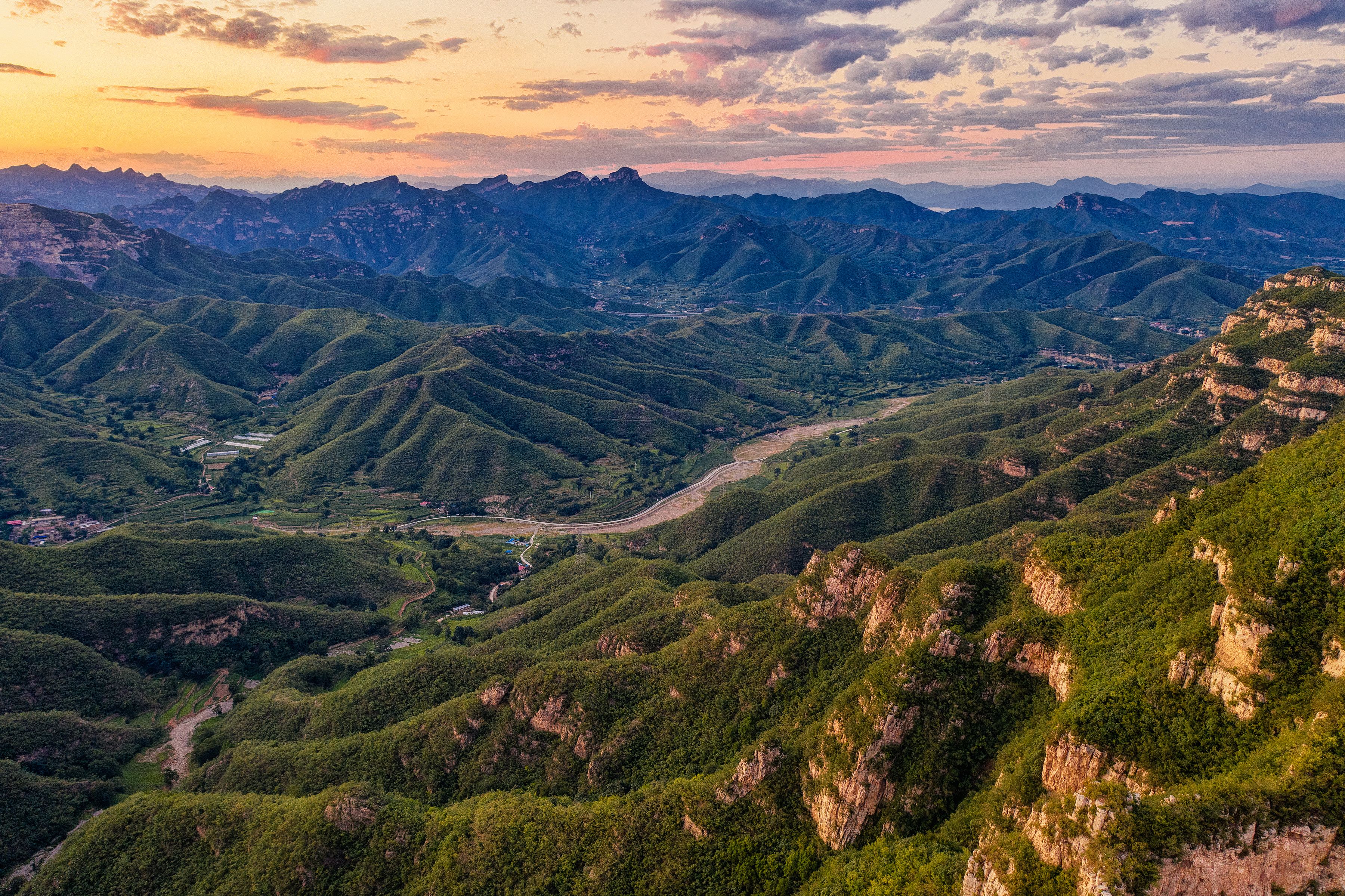 A mountainous landscape with terraced fields and a winding road.
