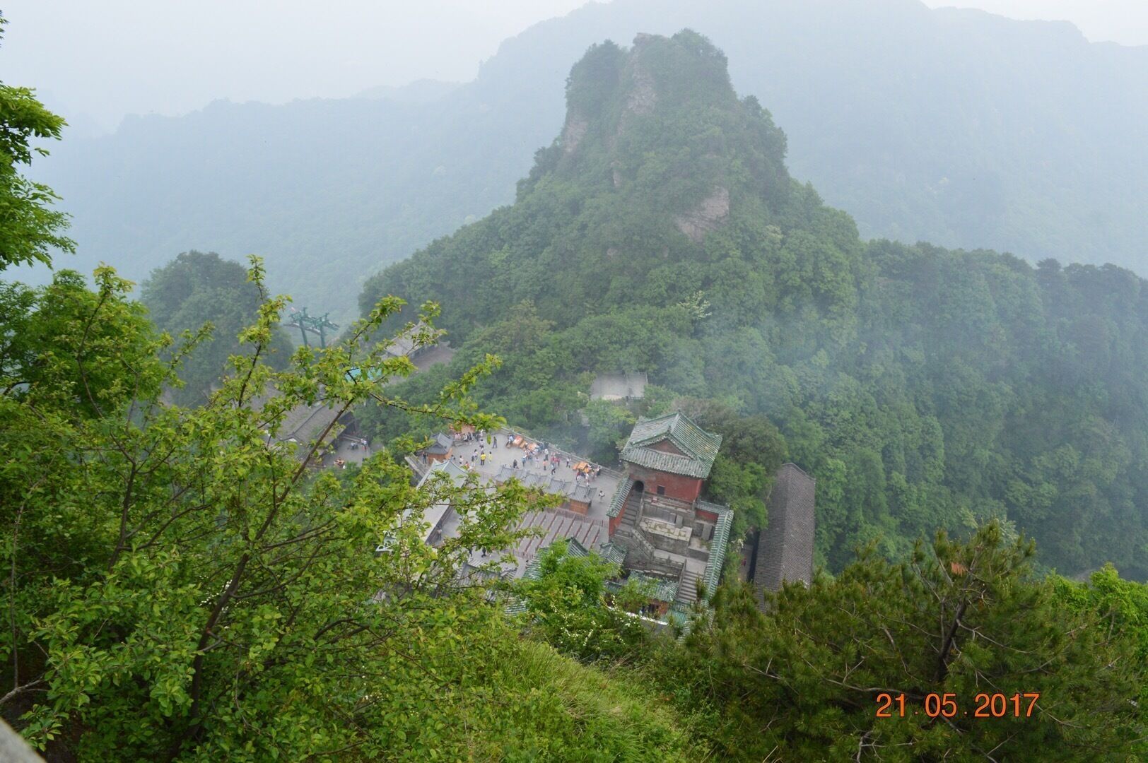 A traditional Chinese temple nestled in a lush, mountainous forest.