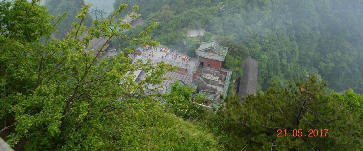 A traditional Chinese temple nestled in a lush, mountainous forest.