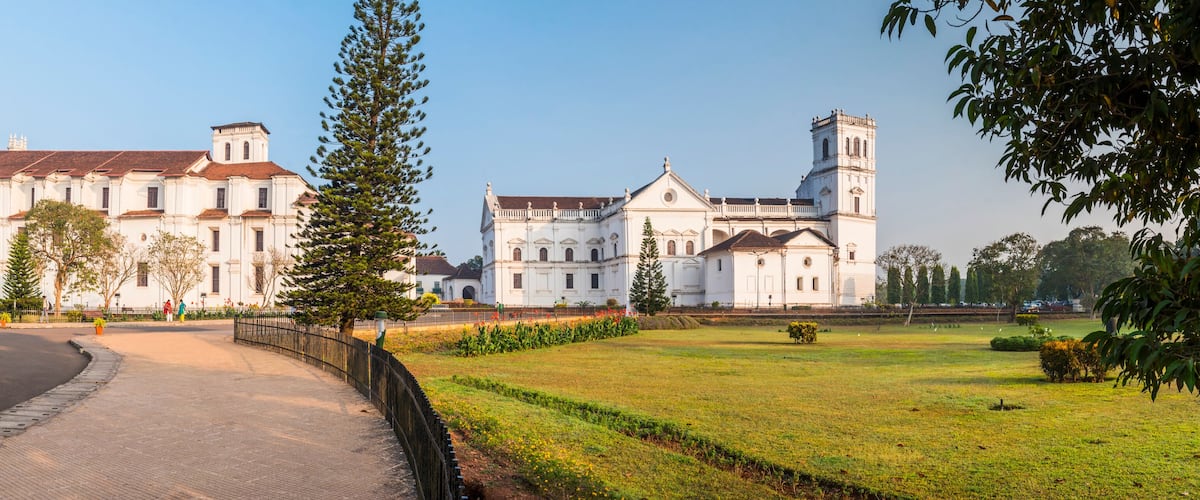 A large white colonial-style building with a prominent tower, surrounded by a well-maintained lawn and a curved pathway.