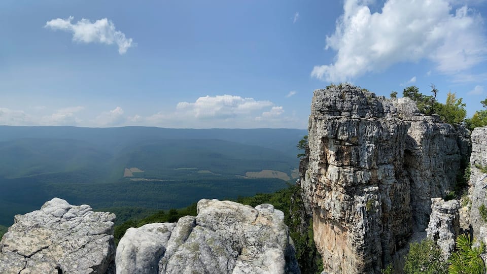 A mountainous landscape with rocky outcrops and dense forest.