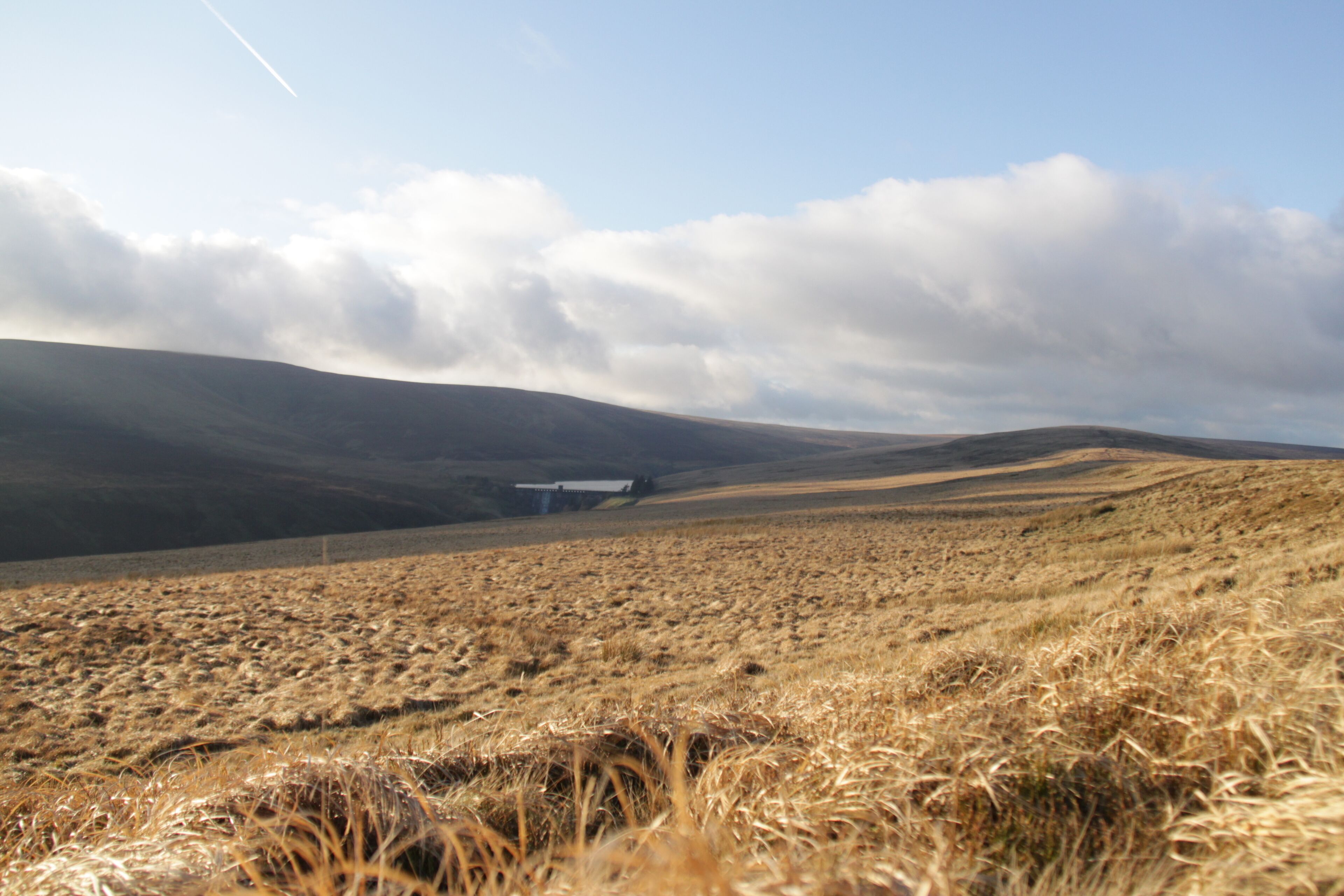 A hilly landscape with a building in the distance.