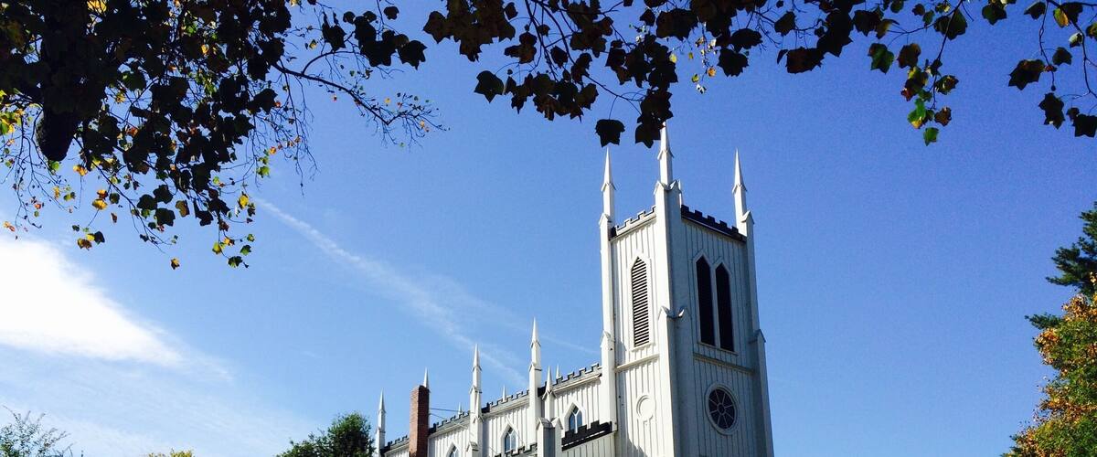 A white church with a tall tower and arched windows.