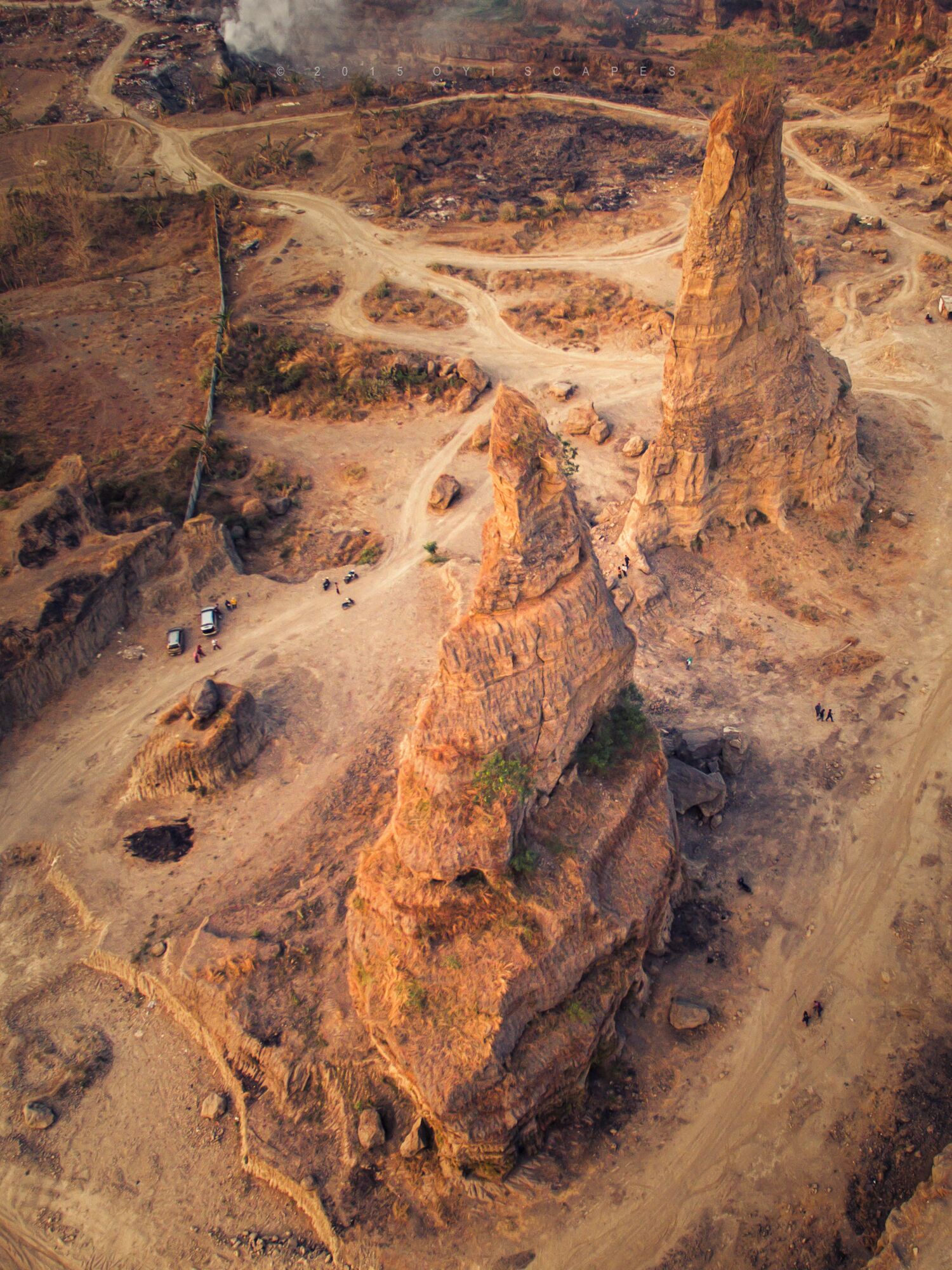 A rugged landscape with two prominent rock formations and winding roads.