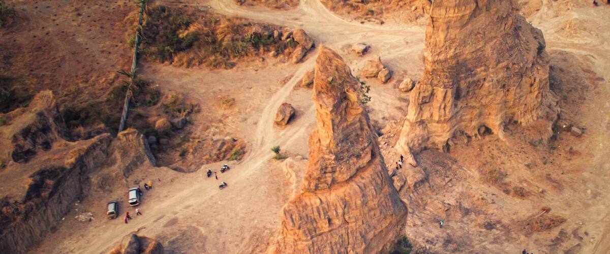 A rugged landscape with two prominent rock formations and winding roads.