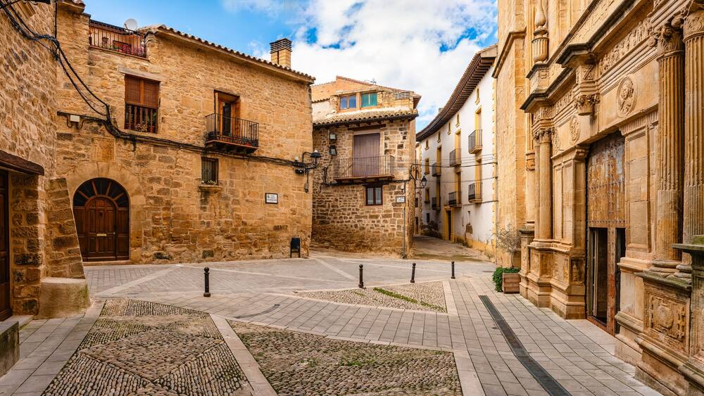 Square with old buildings and facade of a Catholic church in the medieval village of Cretas, Teruel, Matarrana