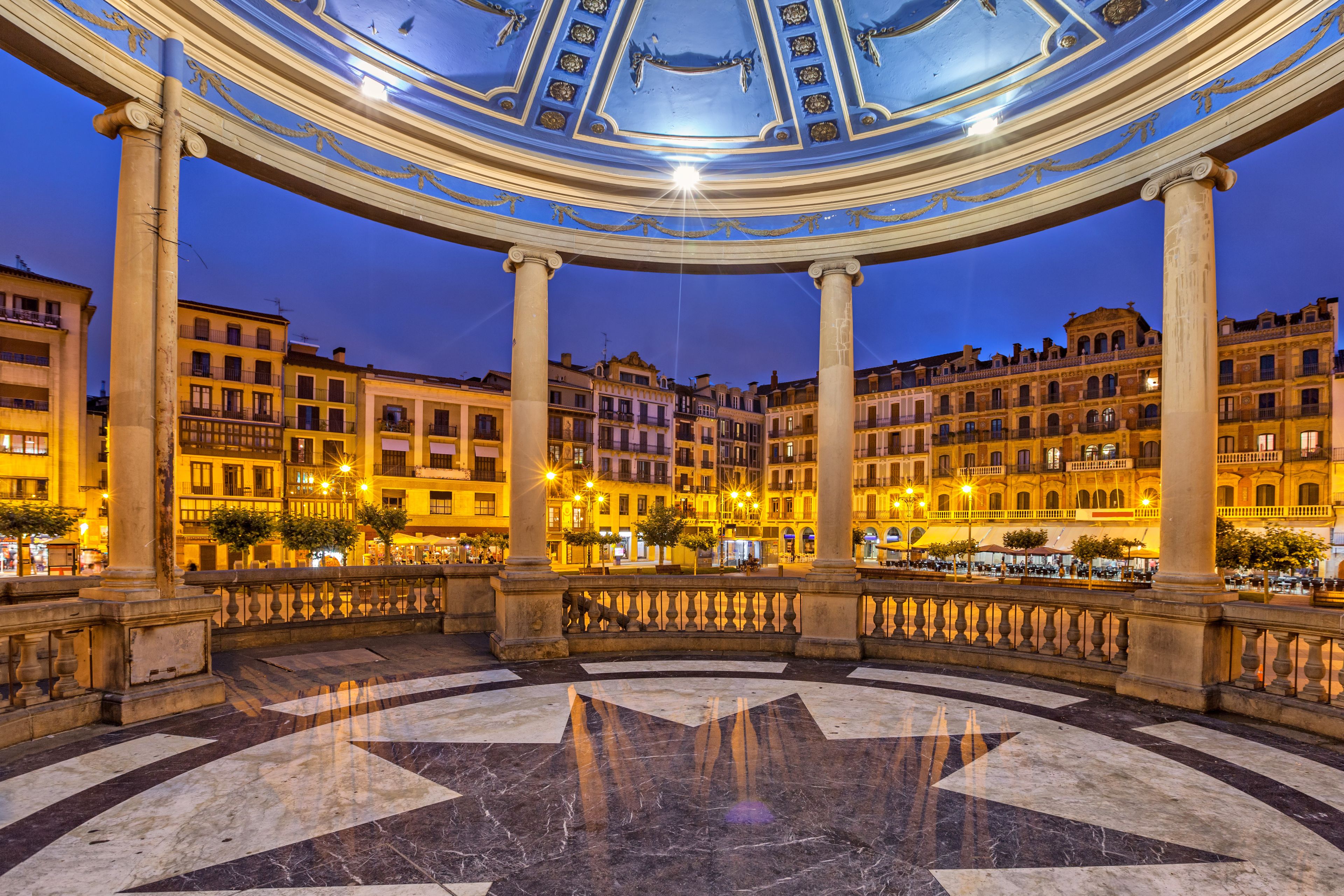 Una imponente estructura arquitectónica con techo abovedado, columnas ornamentadas y un suelo con diseño de estrellas.