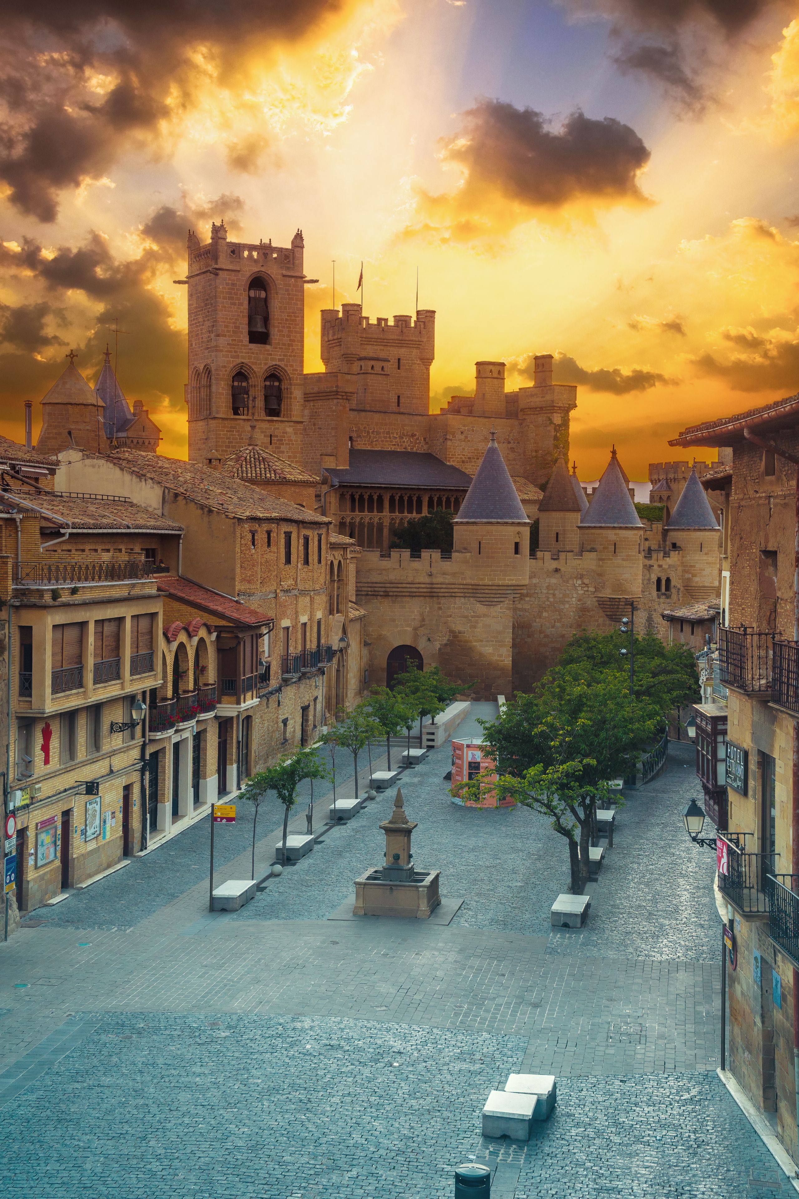 Un castillo medieval con un patio cuadrado, rodeado de edificios históricos con tejados de tejas.