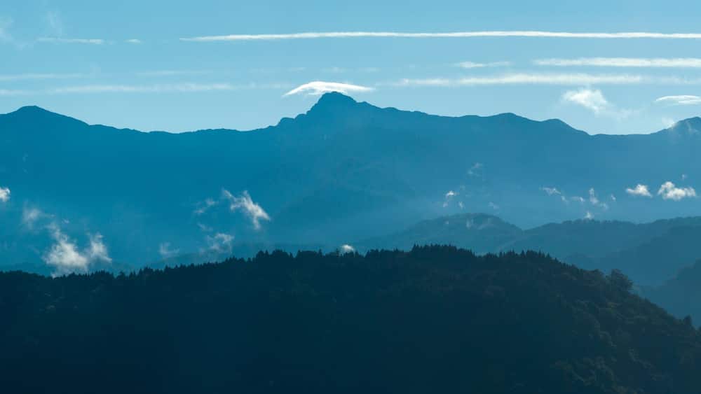 Ein Gebirge mit blauem Himmel und vereinzelten Wolken.