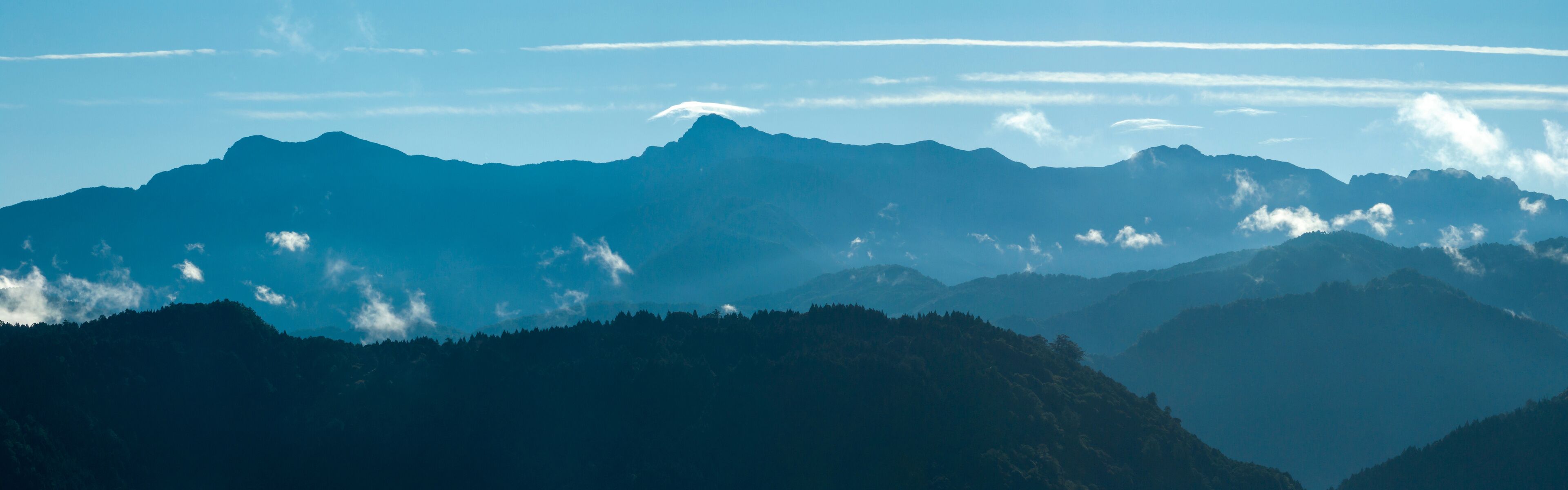 A mountain range with a clear sky and some clouds.