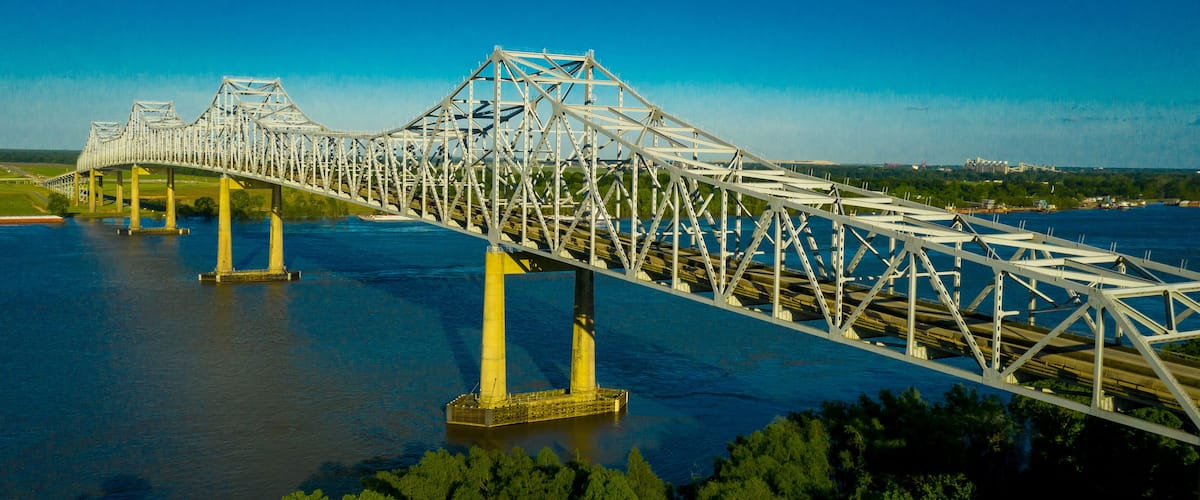 A large steel bridge spanning a wide river with multiple support pillars.