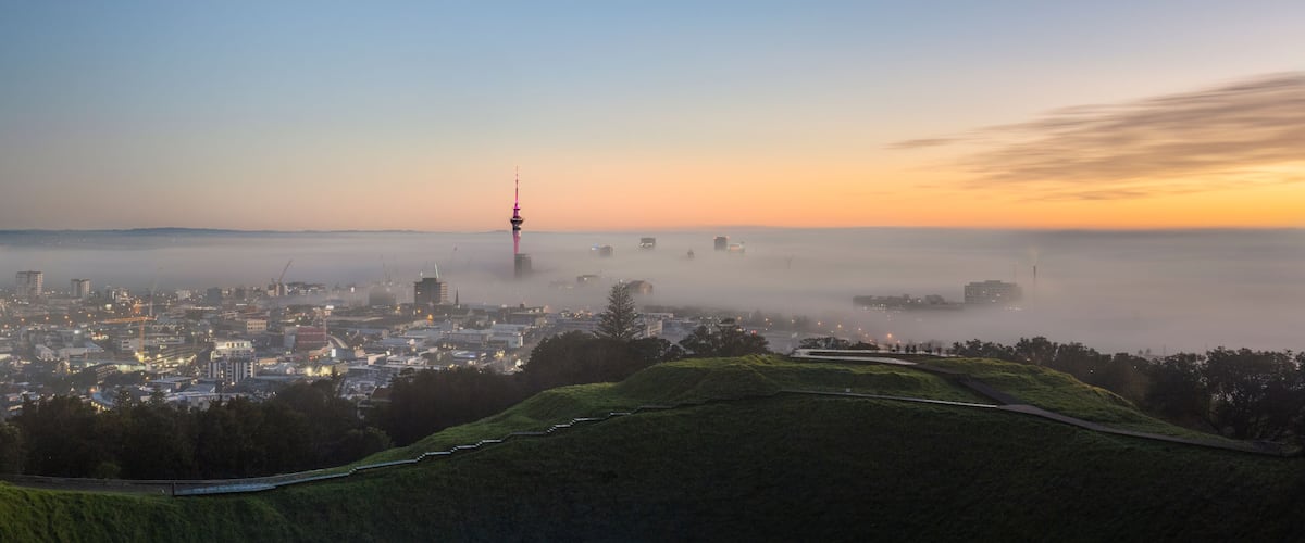 Panoramic view of Sky Tower and Auckland city in the fog, from Mount Eden summit.