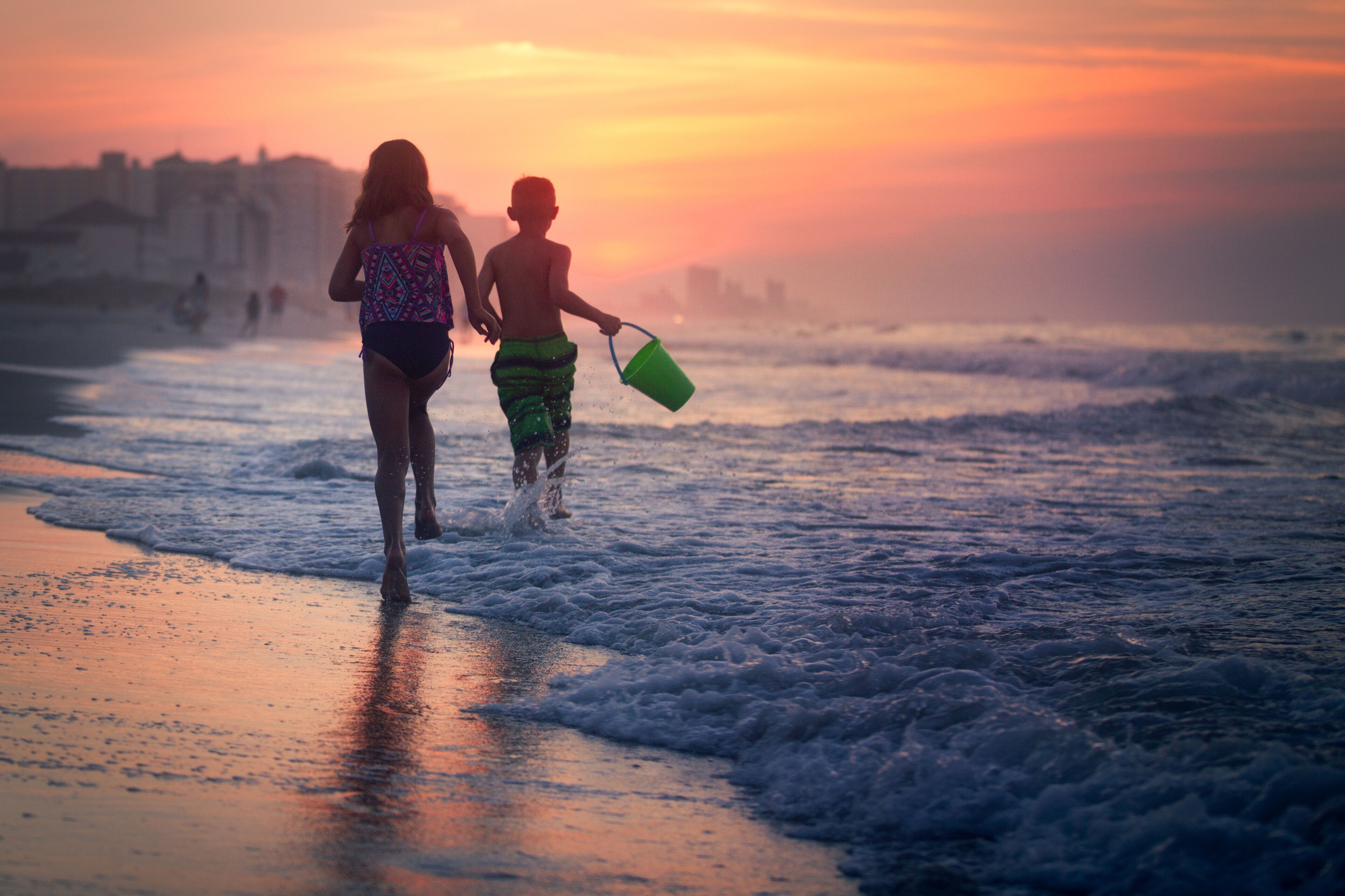 Siblings paddling in sea at sunset, North Myrtle Beach, South Carolina, United States