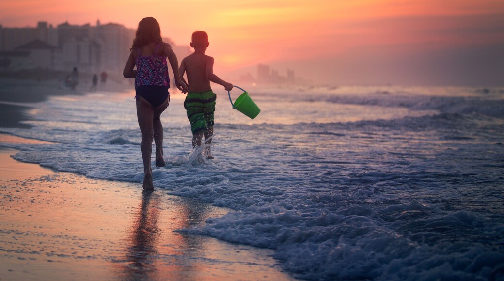 Siblings paddling in sea at sunset, North Myrtle Beach, South Carolina, United States