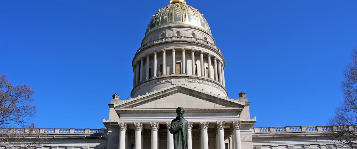 The West Virginia Capitol glows in the sun with the Abraham Lincoln statue in the foreground.
